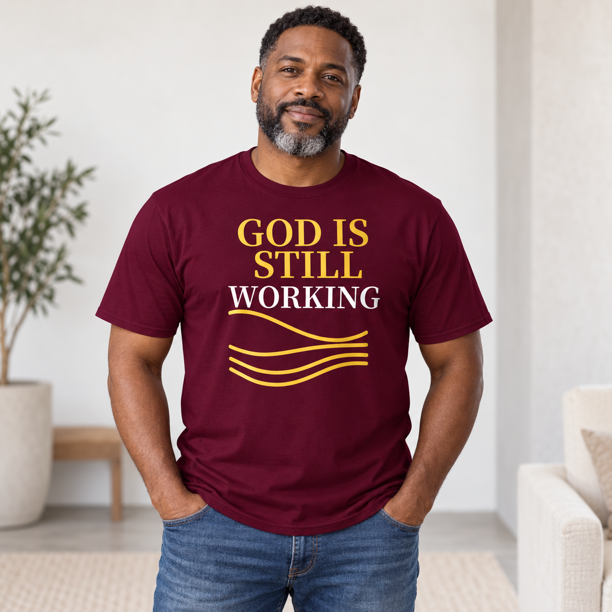 Black man wearing maroon God Is Still Working Christian T-shirt
